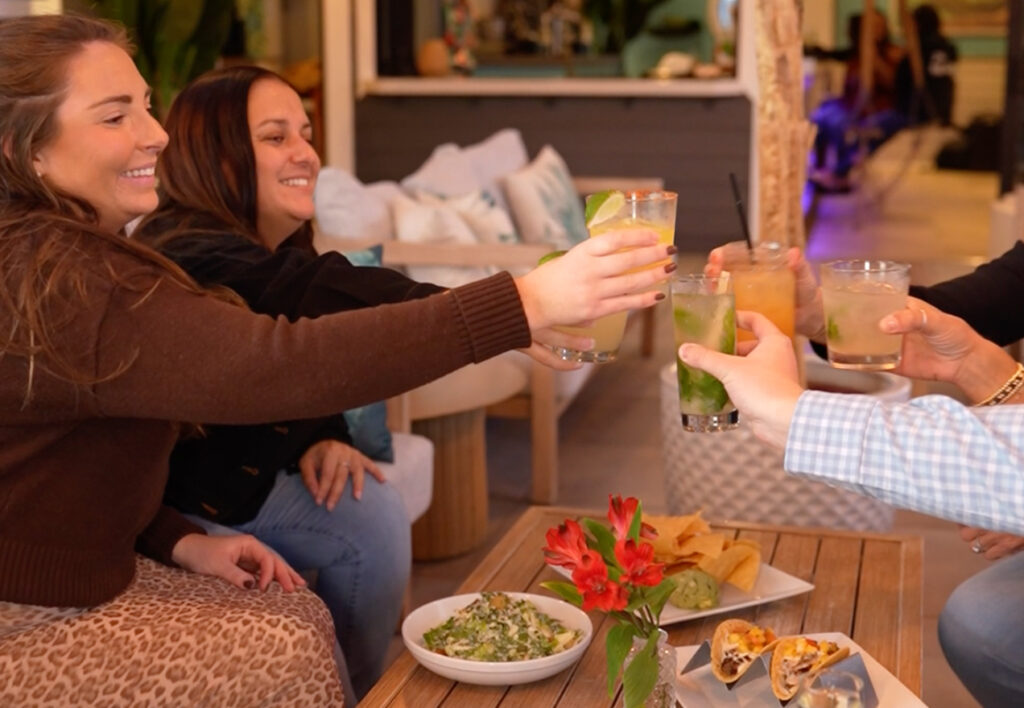 Guests cheering on top of RUMBA Patchogue's Après Rooftop Lounge during Happy Hour
